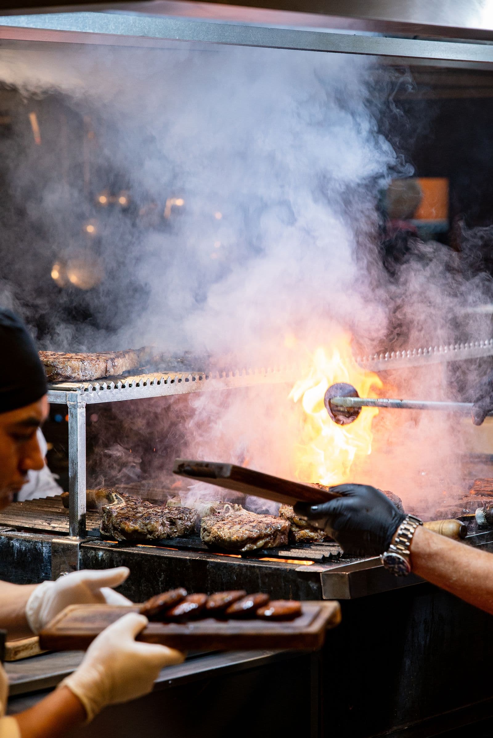 Línea de cocina de un restaurante, con fuego y un cocinero sirviendo un corte